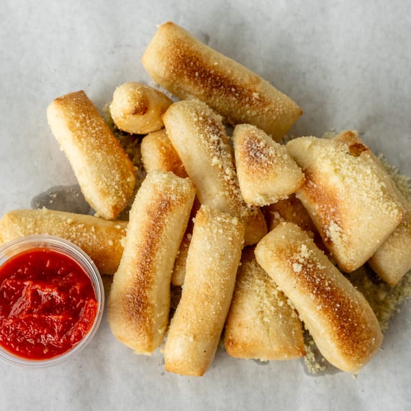 Golden-brown breadsticks, sprinkled with Parmesan cheese, served with a side of marinara sauce.