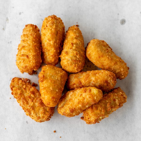 A pile of golden-brown, breaded fried cheese sticks on a white paper background.