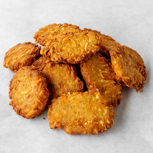 A pile of golden-brown, crispy fried fritters on a white background.