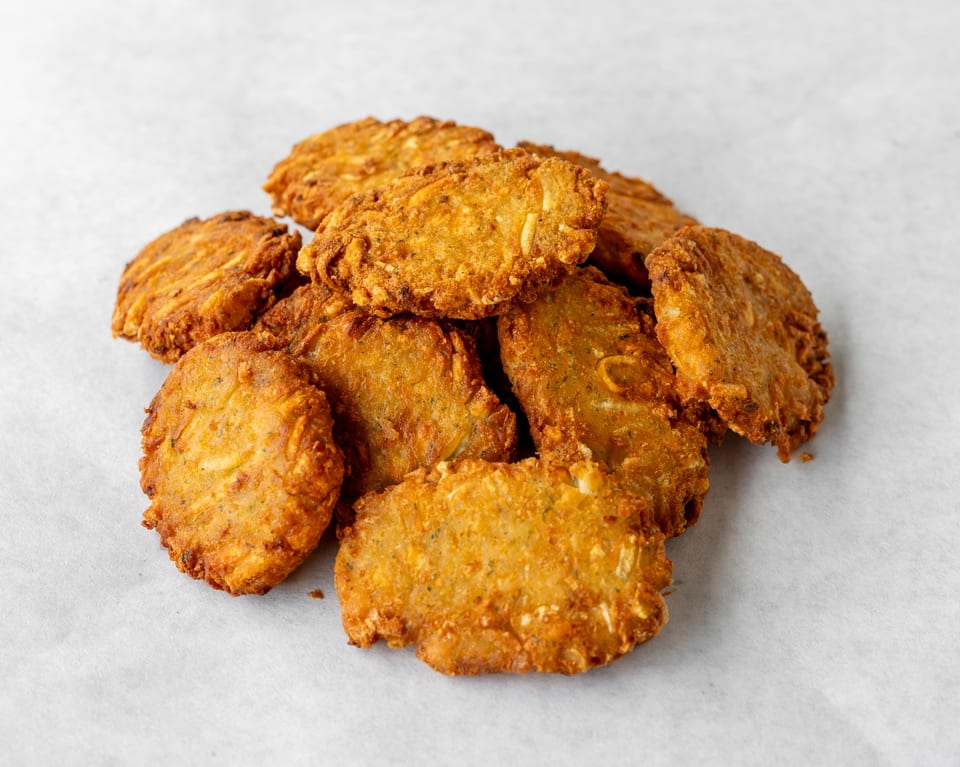 A pile of golden-brown, crispy fried fritters on a white background.