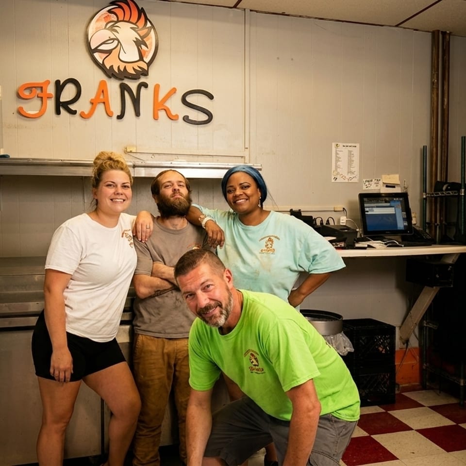 Four smiling restaurant staff members pose in a commercial kitchen with the "Franks" logo visible.